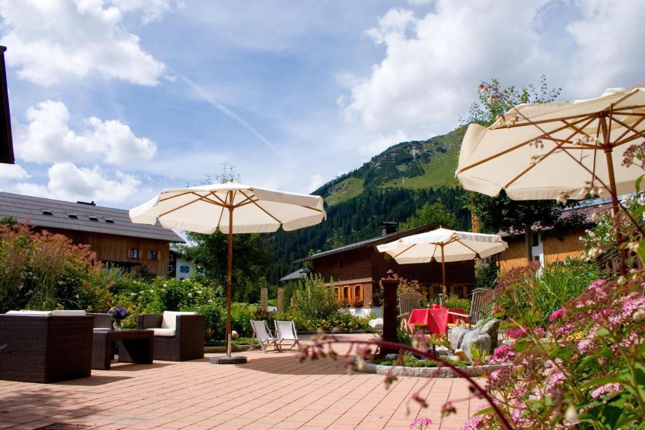 Gemütlicher Garten mit Steinboden und Sonnenschirmen und Sitzgelegenheit Hotel Roggal Lech am Arlberg